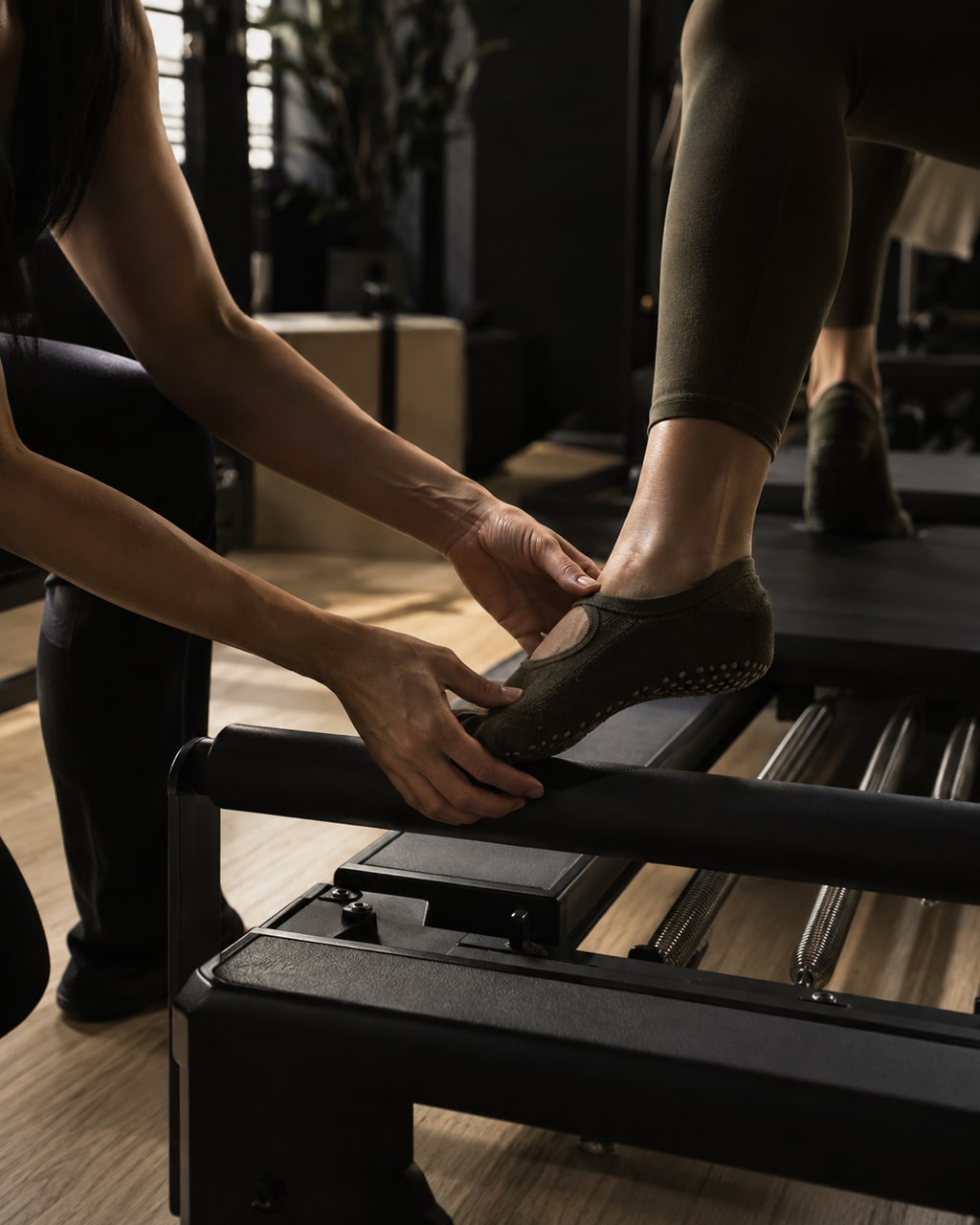 Wen Hui adjusting a client's foot on a reformer footbar.